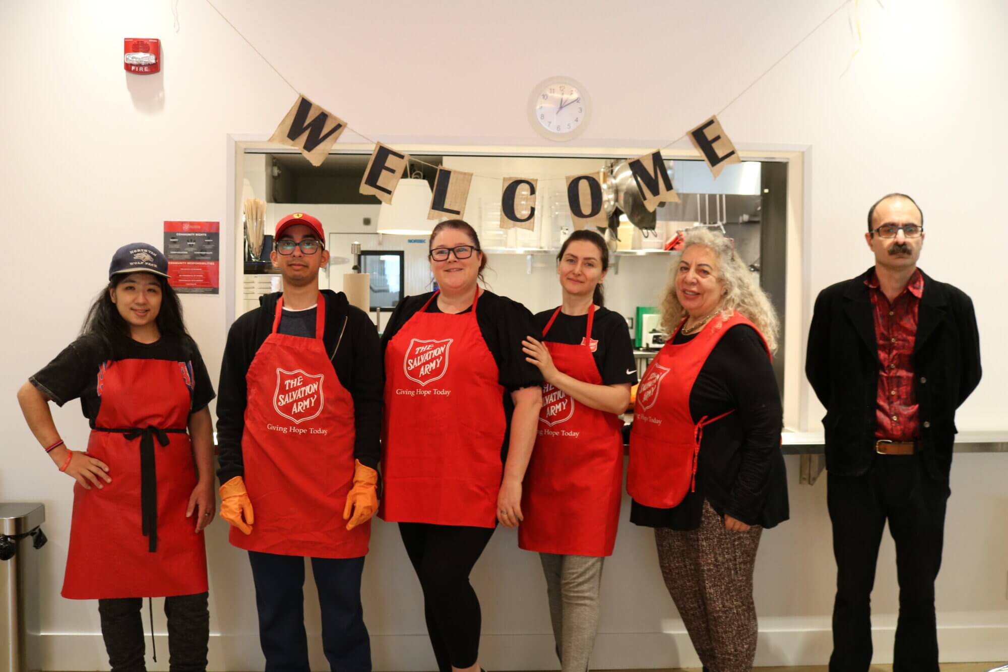 Community volunteers in Salvation Army aprons standing together in a kitchen.